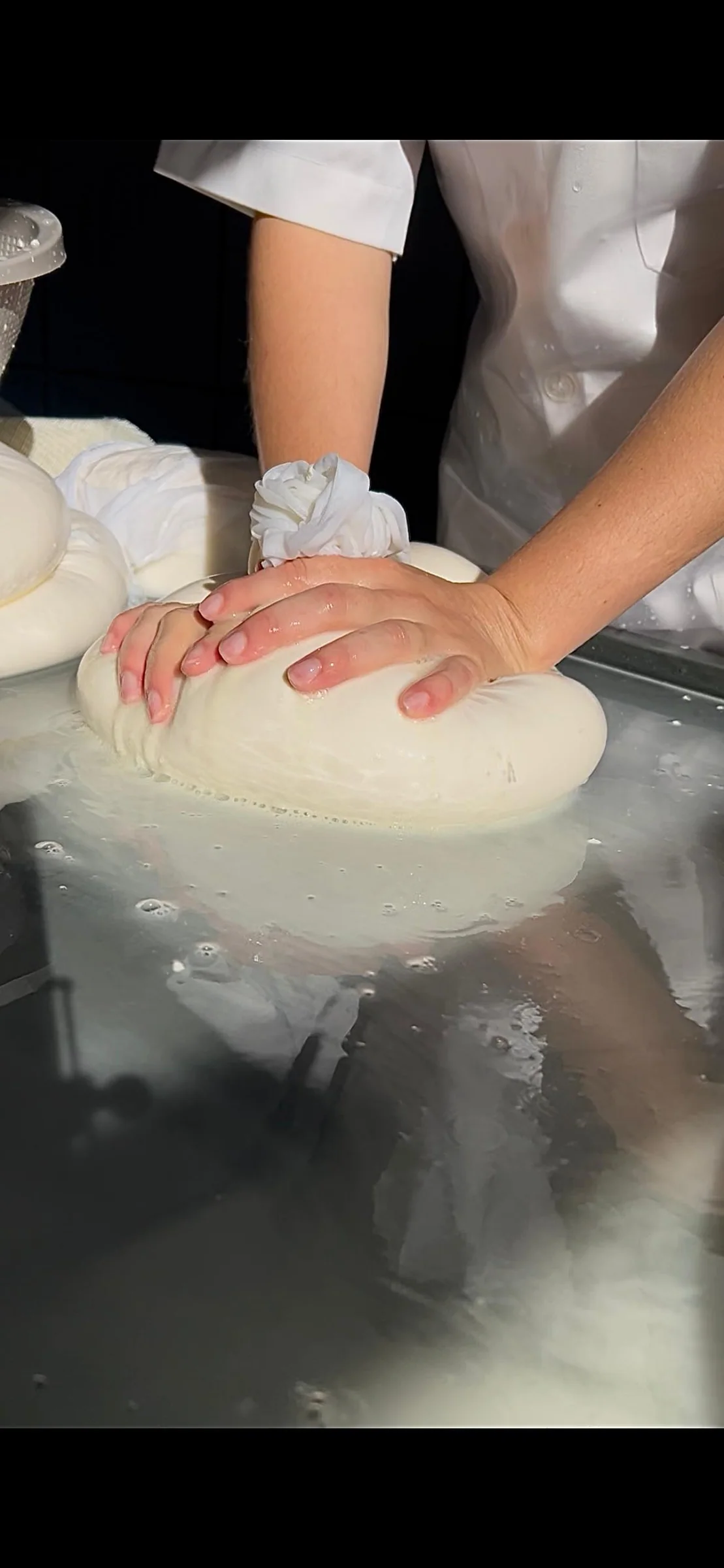 Mãos prensando o Queijo Pérola durante a produção