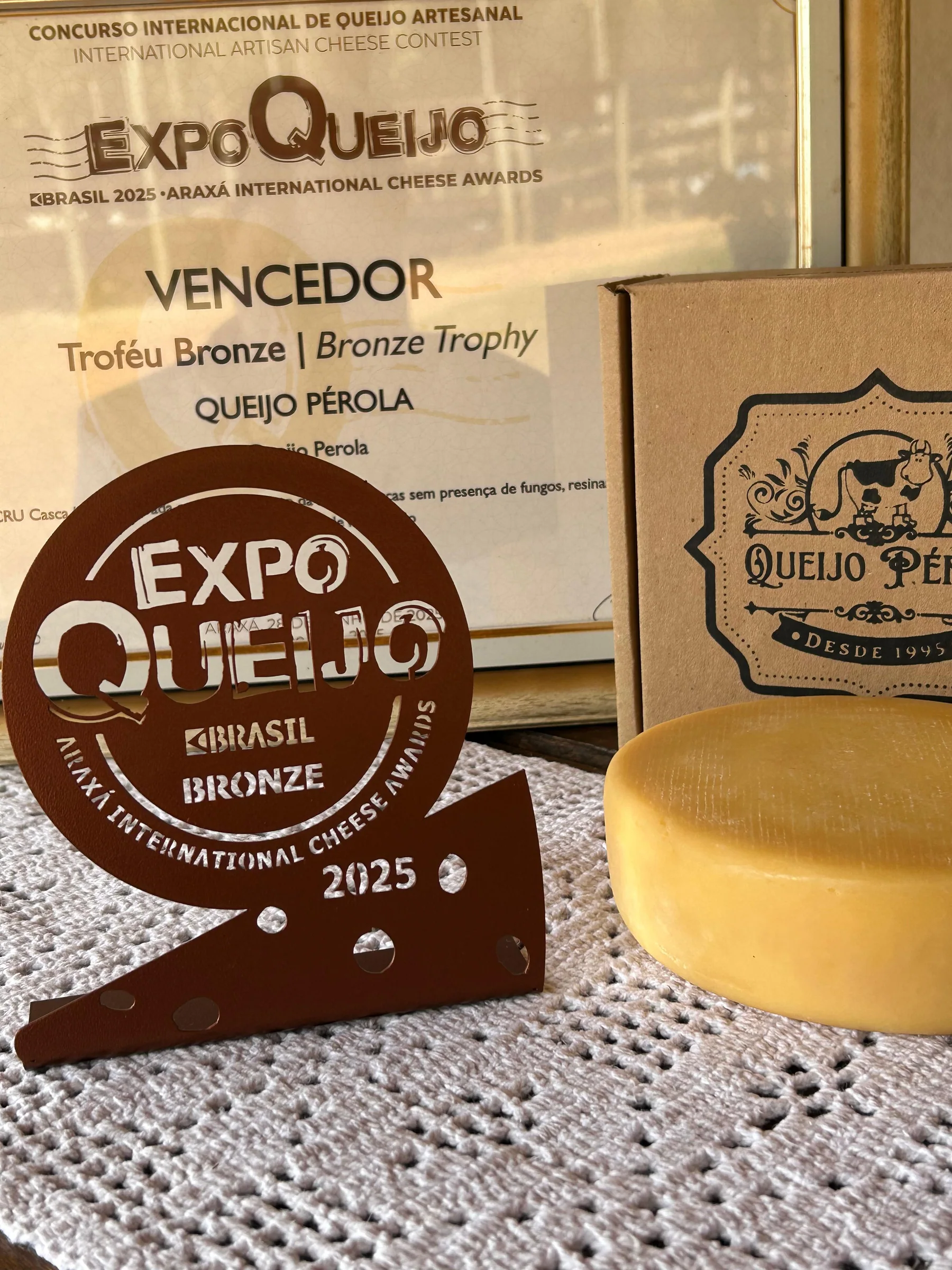 Troféu de bronze da ExpoQueijo ao lado do Queijo Pérola