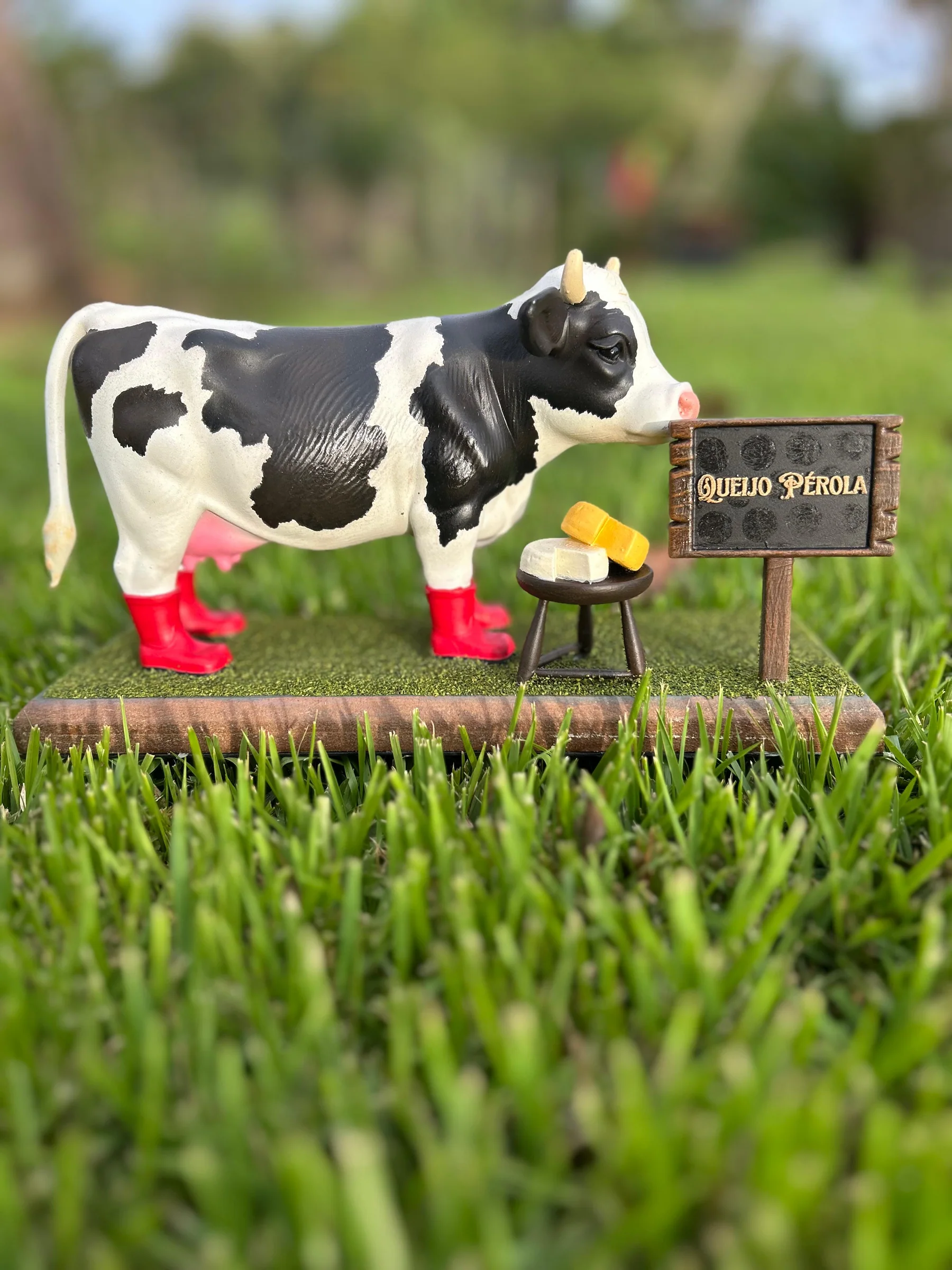 Mascote da Queijo Pérola ao lado da placa da marca